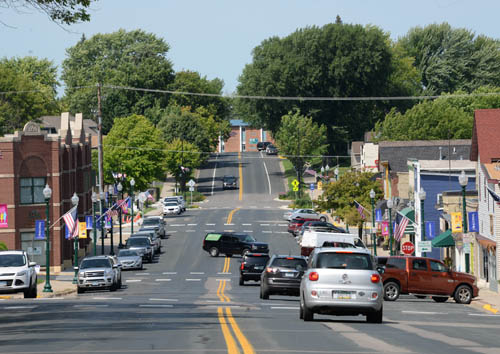 Cars driving and parked on a main street.