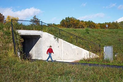 A person walking out of a tunnel under a road.