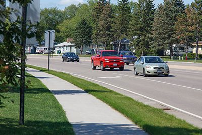 Vehicles on a two-lane road next to a sidewalk.