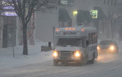 A Metro Mobility vehicle driving during a snowstorm.