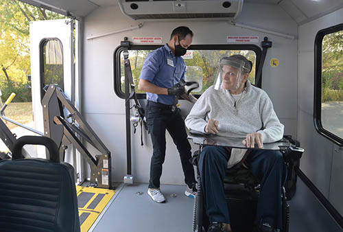 Metro Mobility driver and passenger inside a vehicle, each wearing a mask.