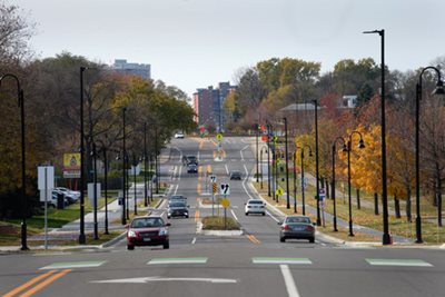 A street with walking paths, bike path, two single lanes of traffic, and a boulevard with turn lanes.