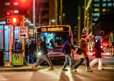 A group of people boarding a Route 535 bus in downtown Minneapolis on a winter night.