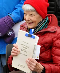 A woman smiling while holding an old report.