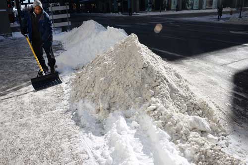 Metro Mobility Provider Liaison Greg Schuck shovels snow from the area where Metro Mobility vans load and unload passengers on Robert Street in downtown Saint Paul.