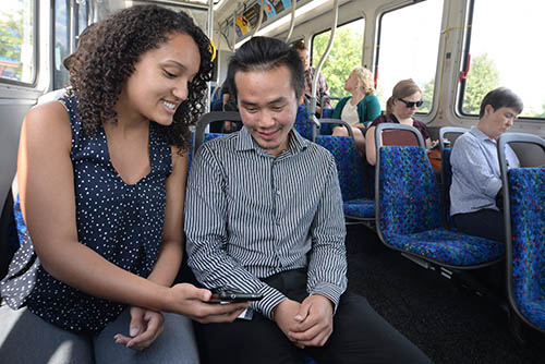 Two people looking at a smartphone on a bus.