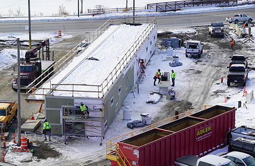 People working on a long, narrow building.