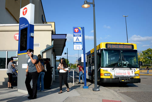 People at a bus stop with a Route 65 bus.
