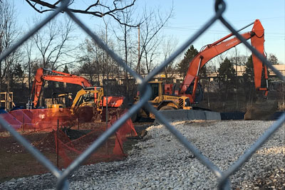 Various orange construction equipment behind a fence.