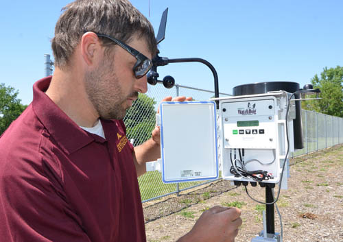 Sam Bauer checks a controller for the U’s study of the drought resistance of a variety of turf grasses.