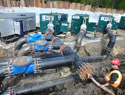 A worker next to large pipes.