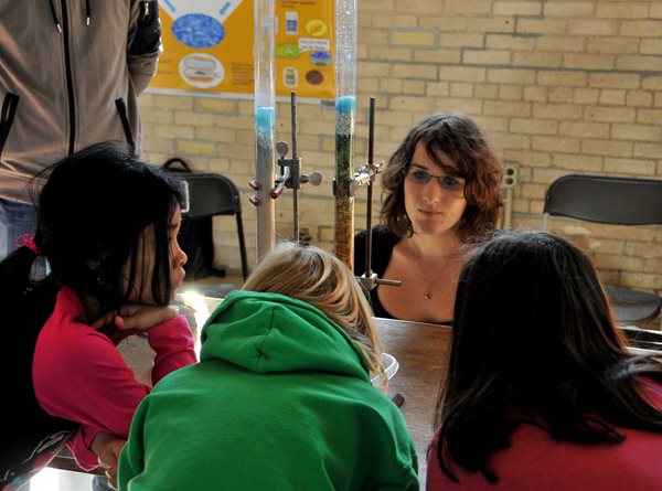 children watch a demonstration of water filtration.