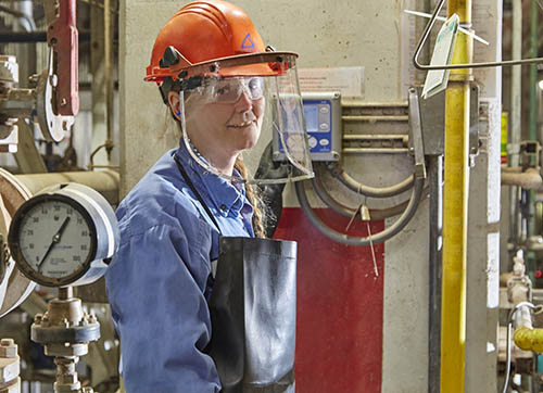 An electrician wearing an orange hard hat with a protective visor.