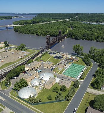 Overhead view of a wastewater treatment plant next to a river.