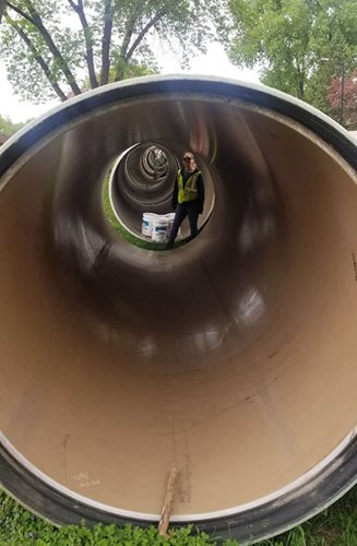 Looking through a pipe at a person at the opposite end.