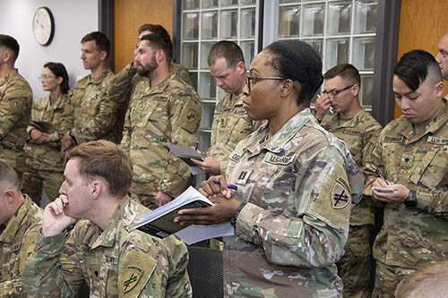 A group of soldiers in uniform taking notes.