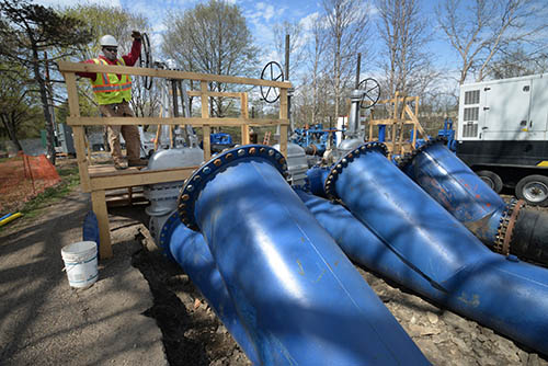 A worker next to three blue pipes.