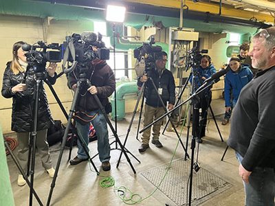 4 people directing TV cameras to a person being interviewed on the right.