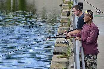 Two people fishing off a bridge.