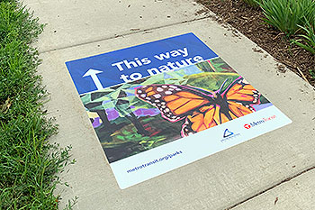 Poster on a sidewalk, pointing visitors to a regional park.