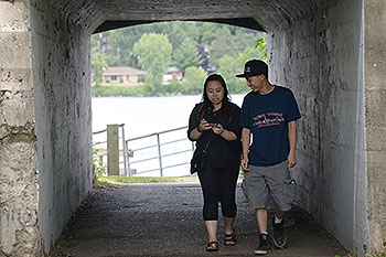 Two people walking while looking at a phone.