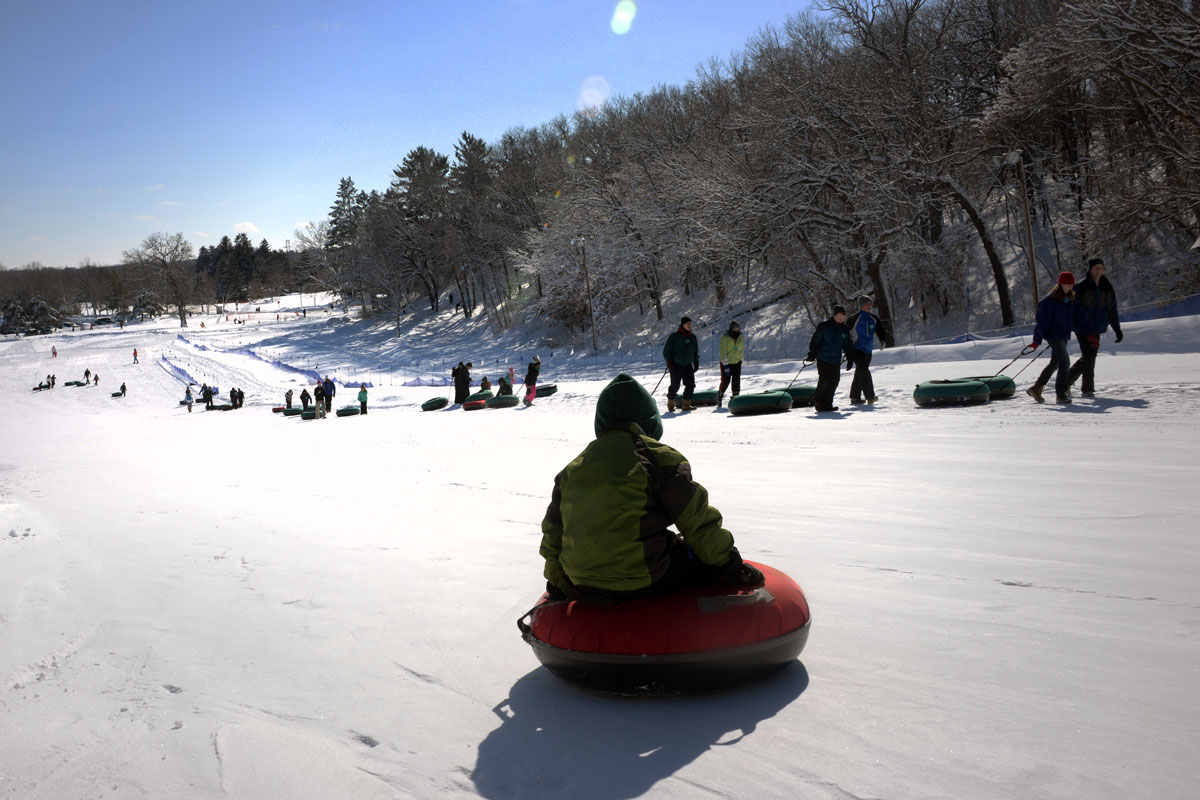A person on a snow tube on top of a sledding hill.