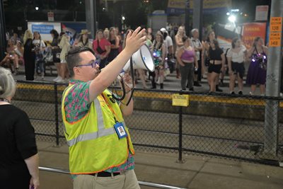 A Metro Transit employee uses a megaphone to direct transit users to where they need to go.