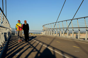 Two people walking on a bridge.