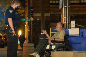 A Metro Transit Police officer talking to a person in a wheelchair.