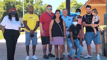 9 people posing at an event in a park.