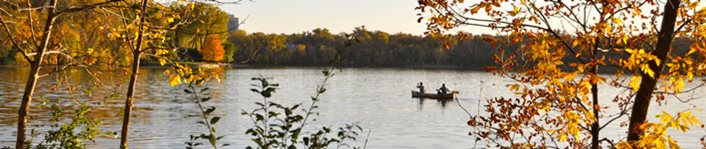Two people canoeing on a Minneapolis lake in autumn.