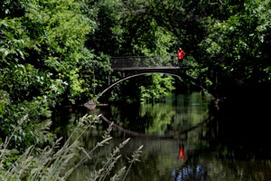 A person stands on a bridge over Minnehaha Creek.