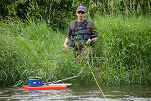 A water quality monitoring staff member takes a water sample at Vermillion River.