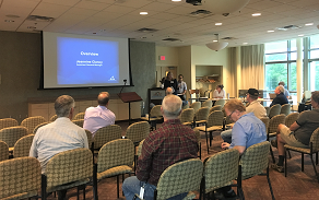 Color photo of community members viewing a presentation on the project at a public meeting.