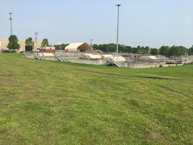 Color photo of Rogers Wastewater Treatment Facility (WWTF) with lawn in foreground and facility equipment and buildings in the background.