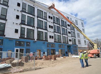 Two workers and construction equipment at the site of a new apartment building in the North Loop of Minneapolis.