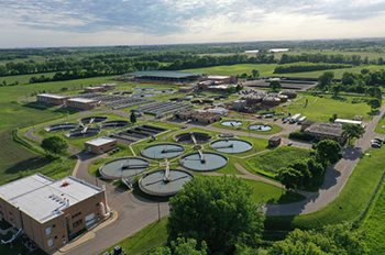 Aerial photo shows the buildings and other wastewater treatment infrastructure at the Empire Plant, surrounded by fields and trees.