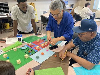 Adults at table use craft materials to create community visions and share ideas.