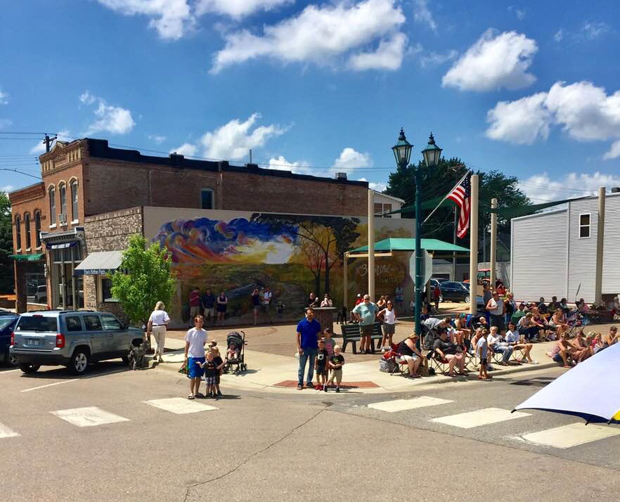 <div class='lb-heading'>BBQ Days Parade </div><div class='lb-text'>The City of Belle Plaine hosts an annual BBQ Days Parade in its Downtown Plaza. In this photo, Lana Beck’s mural is visible behind a group of parade spectators.
</div>