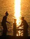 People in the water at sunset.